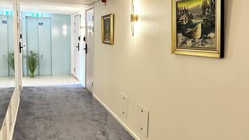 A hallway with carpeted floors, light-colored walls, and framed artwork.