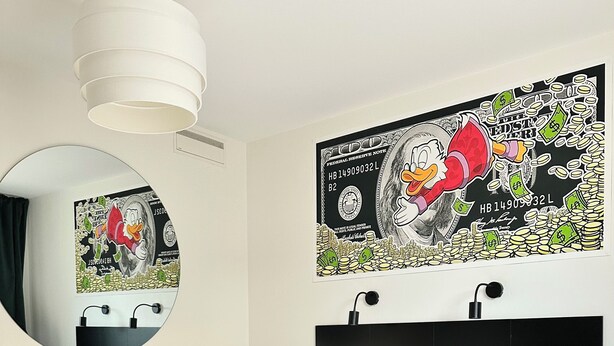 A neatly made bed with white linens and green pillows, a round mirror on the wall, and a large poster of a cartoon character with money. - HOTELL CITY KARLSHAMN (Karlshamn)