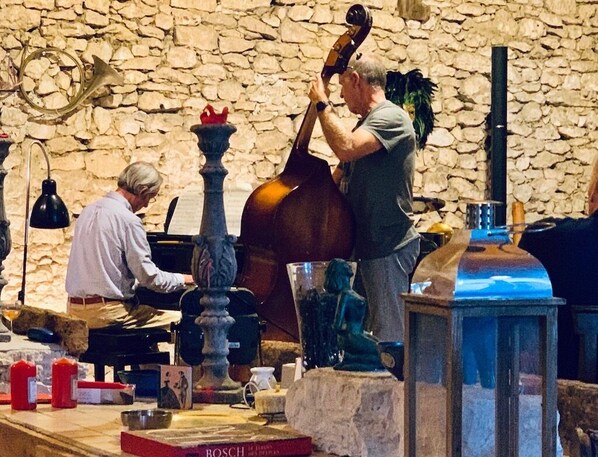 A room with a stone wall, a grand piano, a double bass, and a statue. - Domaine Agenas (Monflanquin)
