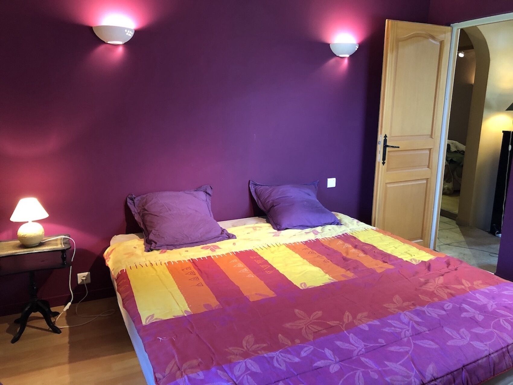 Une chambre à coucher avec un lit, deux oreillers, une table de chevet avec une lampe et deux lampes fixées au mur.