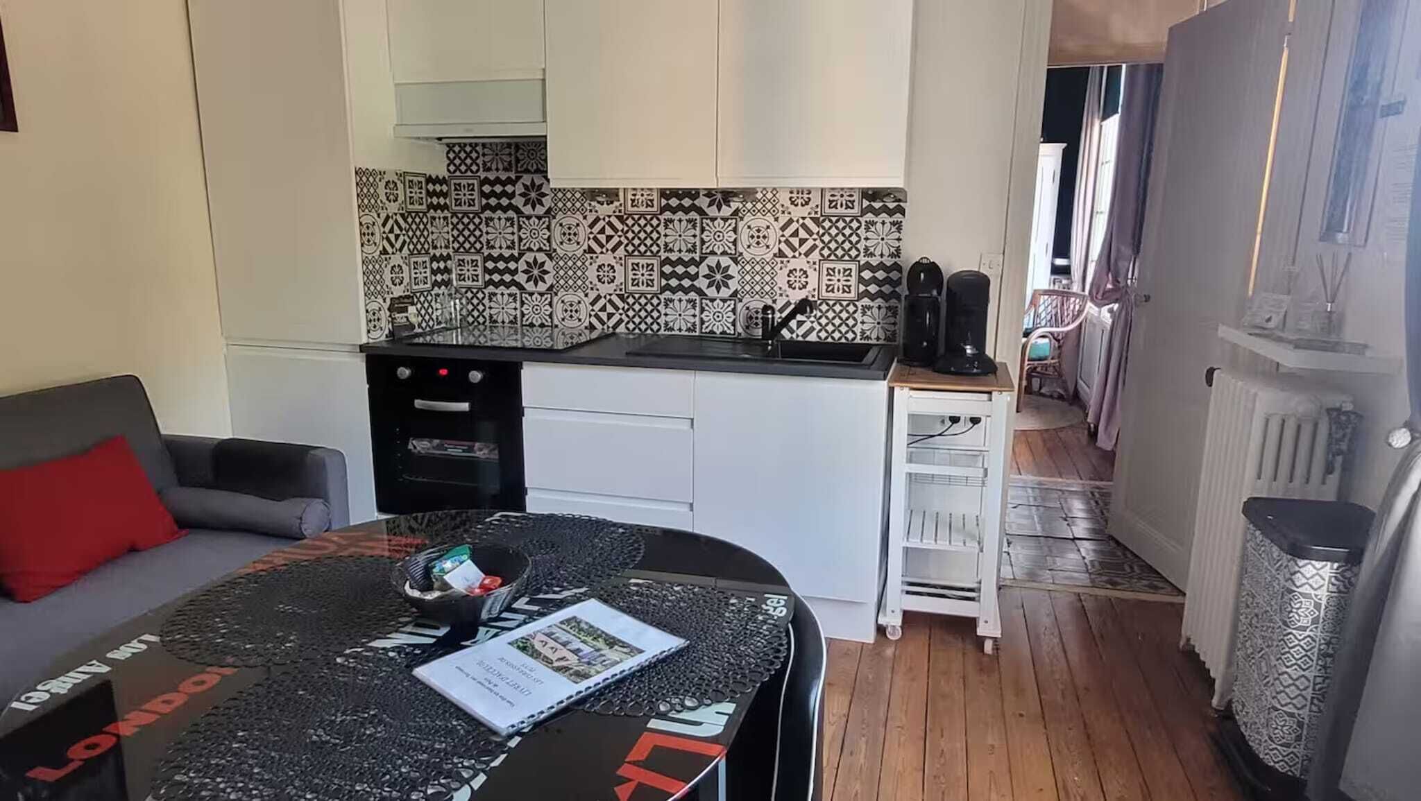 Un espacio habitable compacto con kitchenette, una zona de comedor con mesa y un sofá.