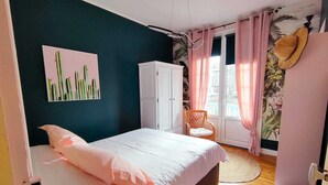 Une chambre à coucher avec un lit, une armoire, une chaise et une fenêtre avec des rideaux.