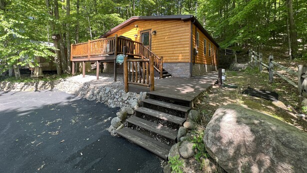 A cabin with a wooden deck, a stone foundation, and a sign indicating it is a campground.