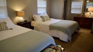 Ein Hotelzimmer mit zwei Betten, einem Nachttisch mit Lampe, einem Schminktisch und einem Spiegel.