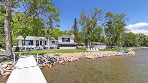 Une maison au bord du lac, avec un quai, une eau claire et des arbres tout autour.