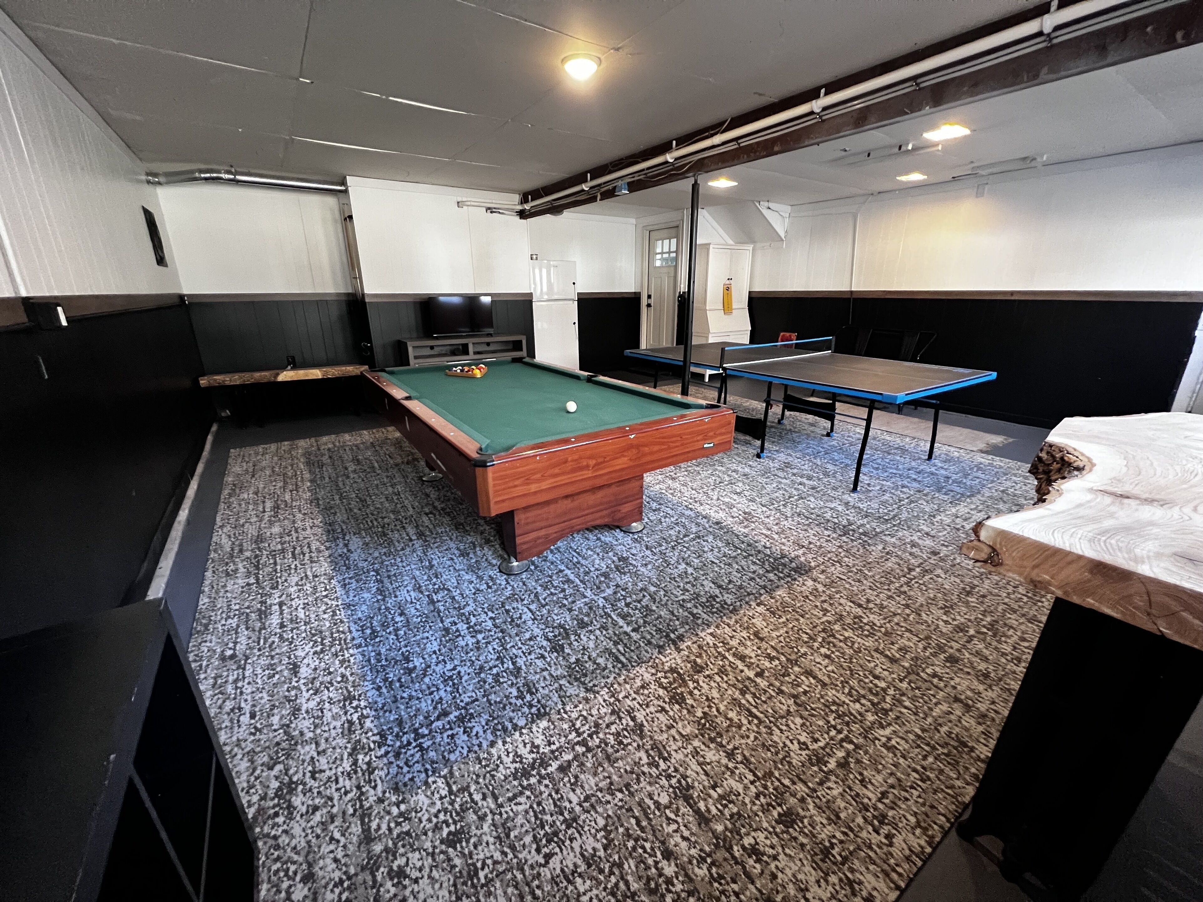 Une table de billard recouverte d’un drap vert, un bâton de billard et une bille.