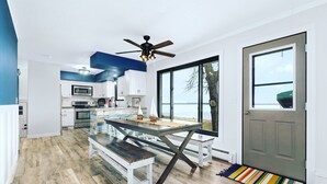Une cuisine moderne avec des armoires blanches, un grand îlot central et une vue sur le lac.