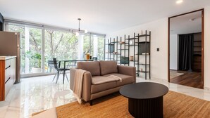 A modern living room with a sofa, coffee table, and a dining area with chairs and a table. - Wynwood House Allan Poe (Mexico City)