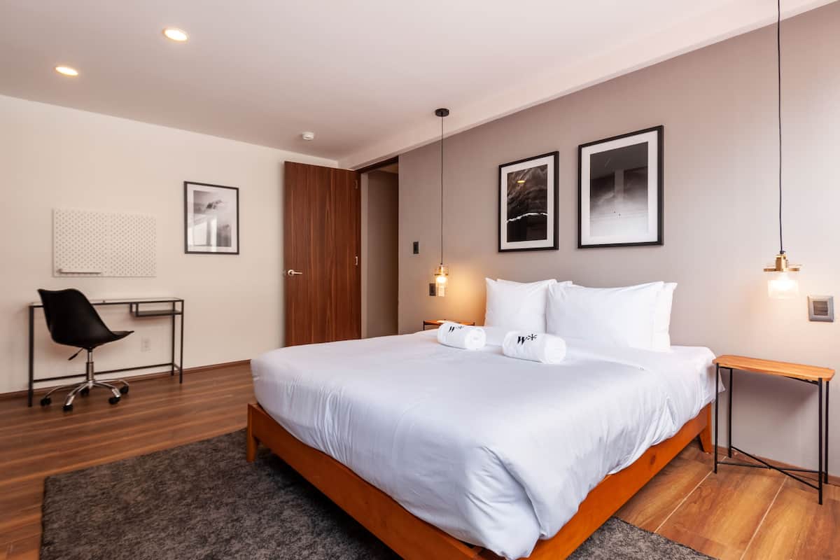 Una habitación de hotel moderna con una cama grande, un escritorio y una silla.