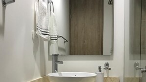 A bathroom with a white vessel sink, a wooden cabinet below, and a mirror above. - Loft Comodo, Iluminado en Usaquen (Bogotá)