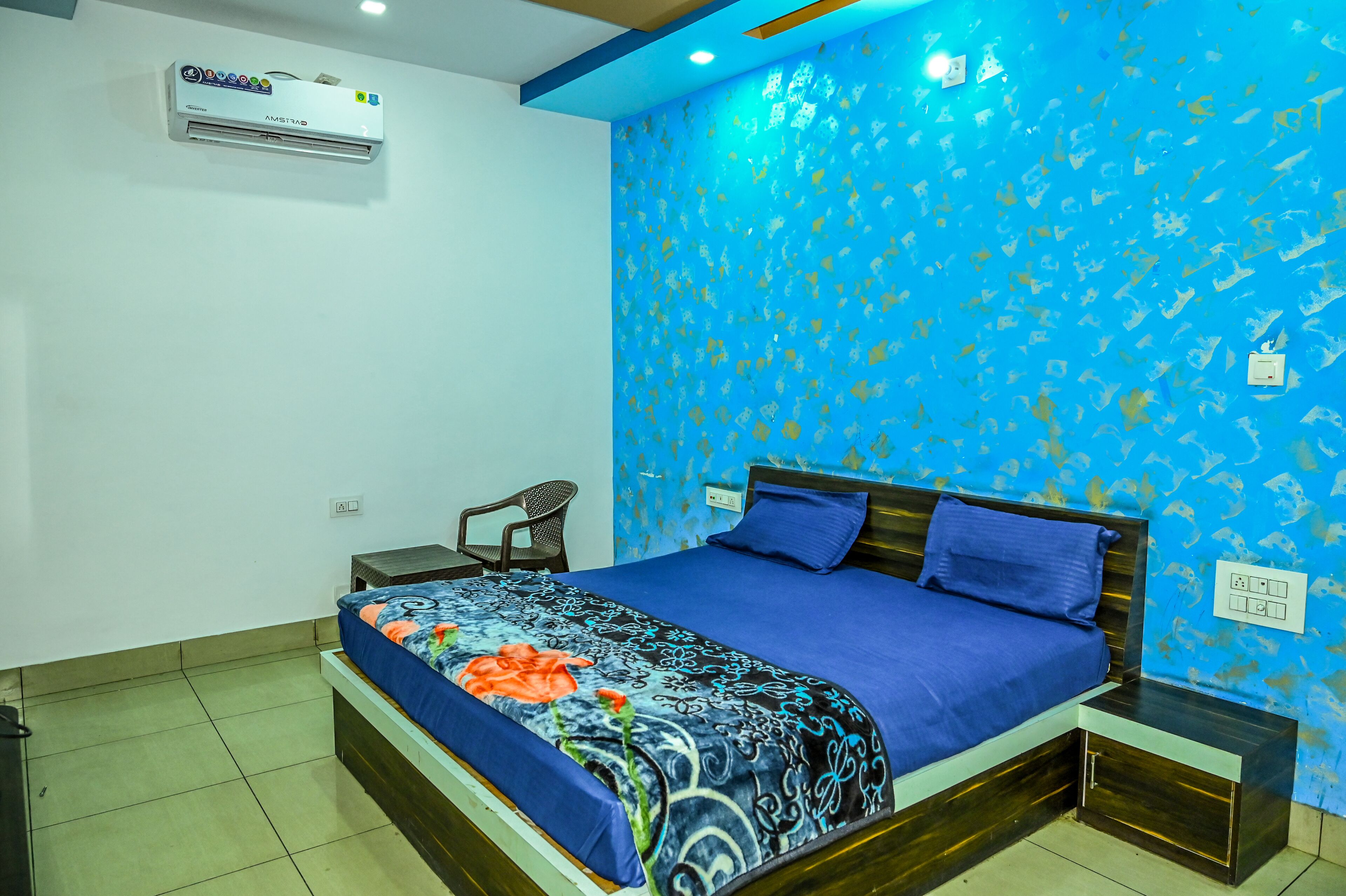 A bedroom with a bed, a nightstand, a chair, and an air conditioner.