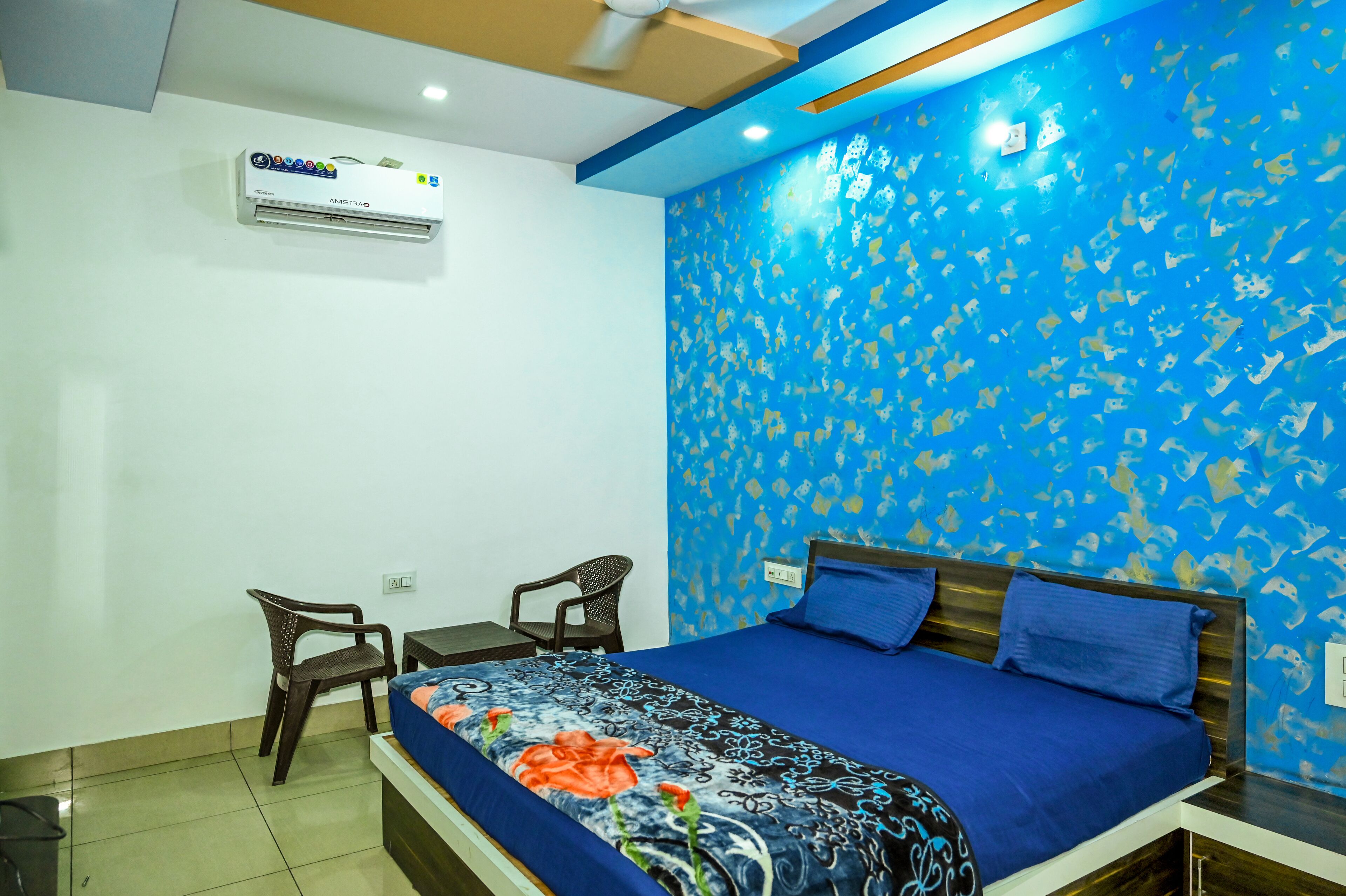 Une chambre à coucher comprenant un lit, deux chaises, un bureau et un climatiseur fixé au mur.