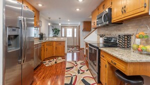 A modern kitchen with wooden cabinets, stainless steel appliances, and a granite countertop.