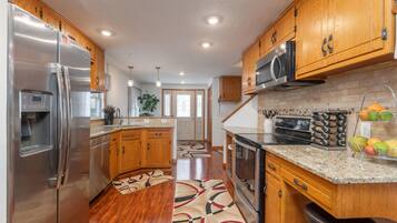 A modern kitchen with wooden cabinets, stainless steel appliances, and a granite countertop.
