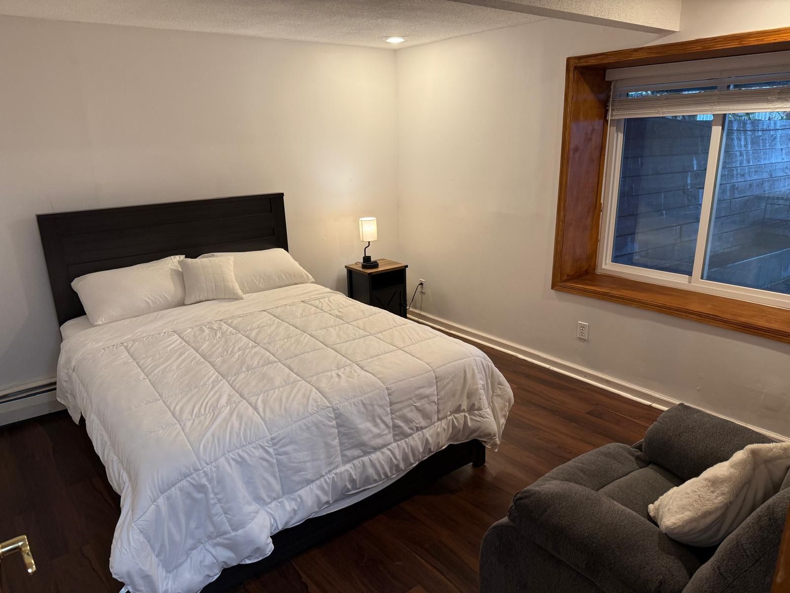 Una camera da letto con un letto, un comodino, una lampada e una finestra.