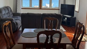 A living room with a sofa, TV, dining table, and chairs.