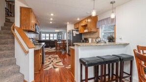A spacious kitchen with wooden cabinets, a granite countertop, and a bar area with stools.