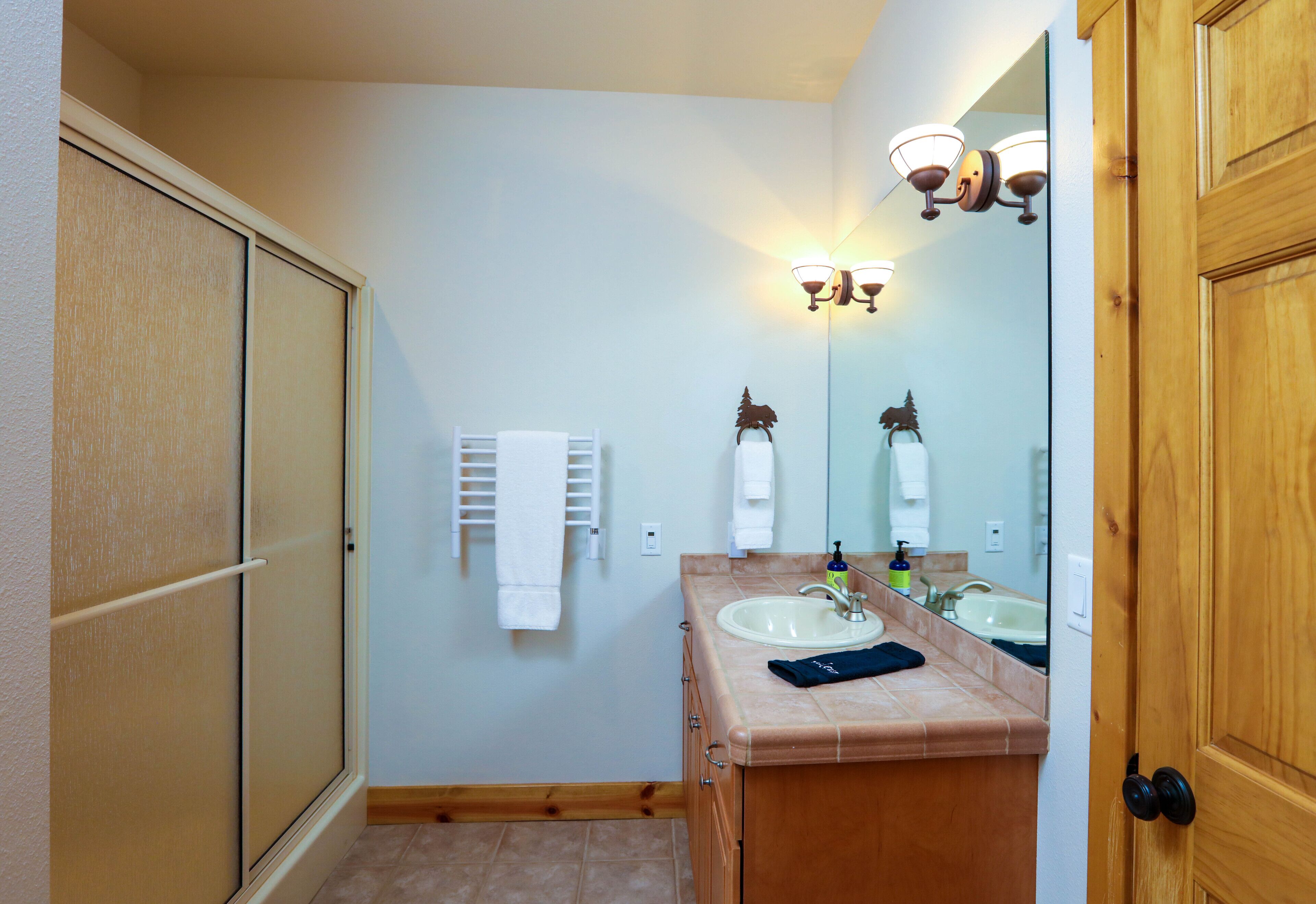 Une salle de bain avec un meuble-lavabo en bois, un évier, un miroir et un porte-serviettes.
