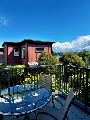 A red building with a balcony, a glass table, and chairs.