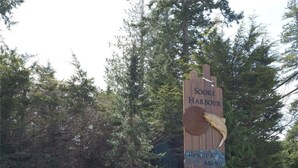 Un senyal de fusta del Sooke Harbour Resort & Marina, envoltat de roques i arbres.