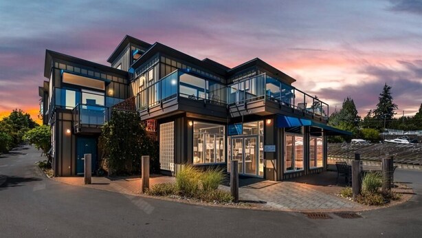 A modern multi-story building with large glass windows, a covered outdoor area, and a driveway. - Sooke Oceanview Penthouse - Family Friendly with Ocean Views (Sooke)