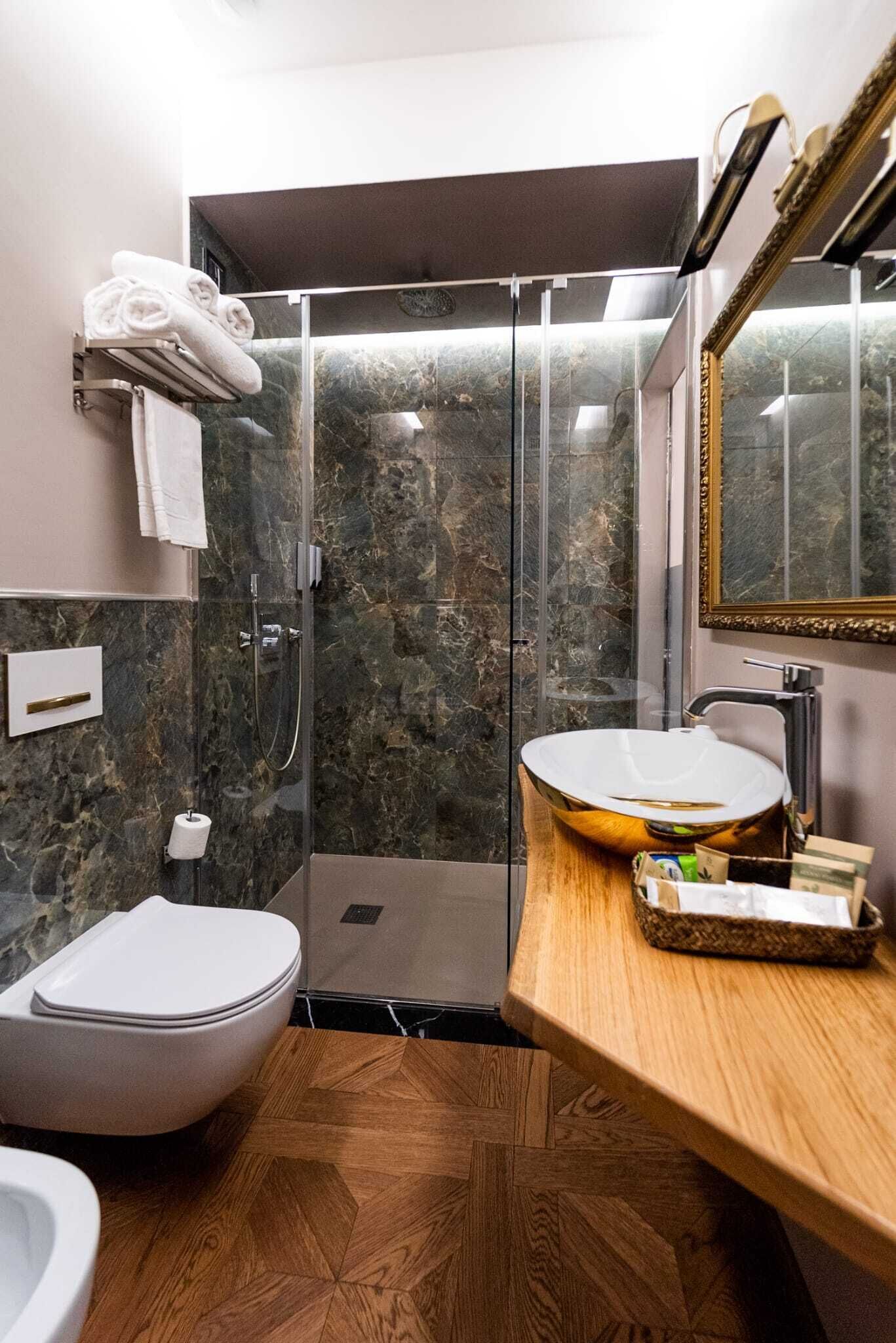 A modern bathroom with a glass-enclosed shower, a white sink, and a wooden vanity.