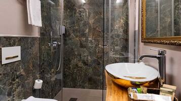 A modern bathroom with a glass-enclosed shower, a white sink, and a wooden vanity.