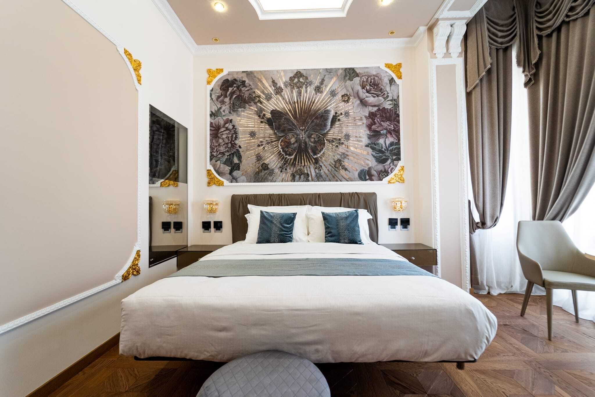 Un grand lit avec une tête de lit, une œuvre d’art accrochée au mur, des lampes de chevet et une chaise.