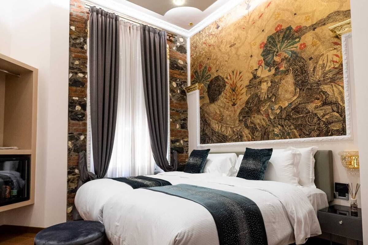 Ein modernes Schlafzimmer mit einem großen Bett, einer Wand aus Stein, einer dekorativen Deckenleuchte und einem großen Wandteppich.
