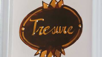 A wooden sign with the word "Tresure" on a white wall.