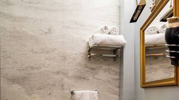 A bathroom with a wooden vanity, a gold sink, a bidet, and a towel rack with towels.