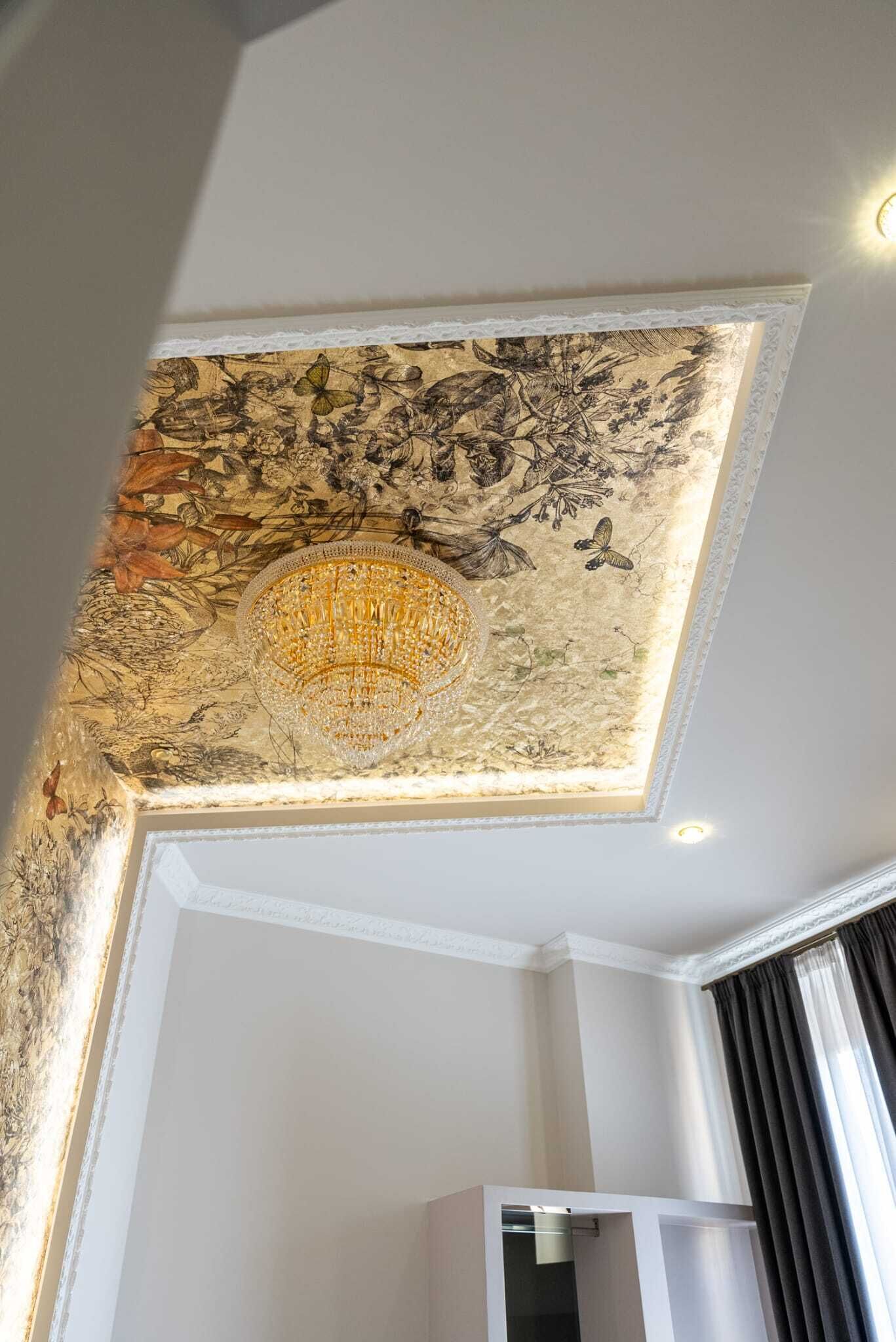 A room with a ceiling mural, a chandelier, and a wardrobe.