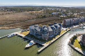 Hotel na orla marítima com edifício central e um cais com barcos.
