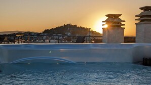 A rooftop pool with a view of a cityscape and a hill in the background.