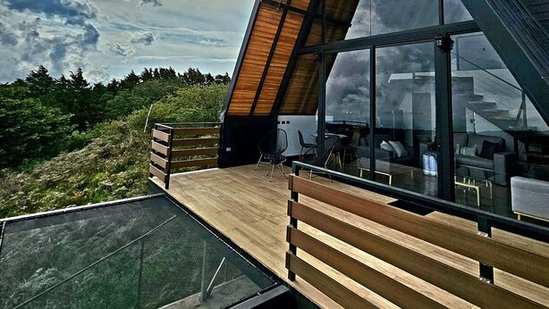 Un edificio moderno con techo inclinado, ventanas grandes y una terraza de madera.