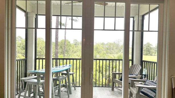 A covered outdoor area with a table and chairs, a bench, and a view of greenery.