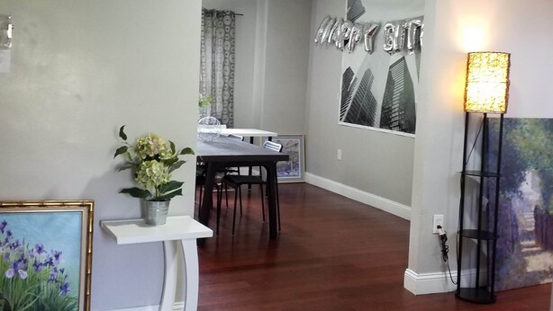 A modern living room with a dining area, featuring a white console table, a potted plant, and a framed picture. - Fairmount House at The Mann (Philadelphia)