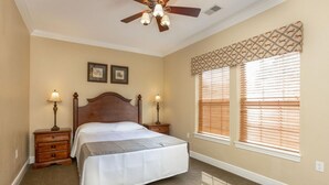 A bedroom with a large bed, two bedside tables, a ceiling fan, and a window with blinds. - Downtown 1BR Condo in Great Rock Resort (Branson)