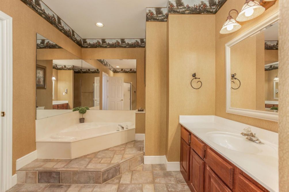 A bathroom with a large mirror, a bathtub, and a vanity with a sink.