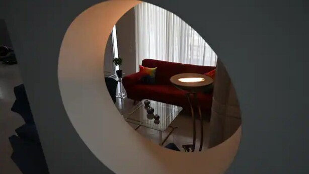 Una ventana circular con un sofá rojo y una pequeña mesa redonda en una habitación moderna.