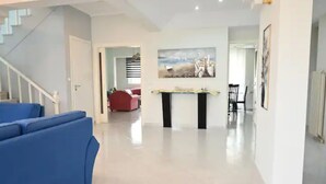 Un área de estar amplia con una escalera, un comedor con mesa y sillas, y un cuadro en la pared.