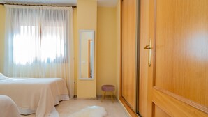 Ein Hotelzimmer mit einem Bett, einem kleinen Hocker, einem Spiegel und einem Kleiderschrank.