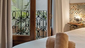 A hotel room with a bed, two towels, a nightstand, a lamp, and a view of a balcony with a palm tree. - casa carpa andalucia II (Nerja)
