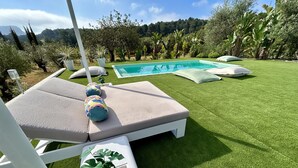 Et poolområde med liggestole og en plantekasse med tropiske planter.