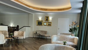 A spacious lobby with a curved ceiling, a seating area with armchairs and a round table, and a staircase in the background. - Mleczarnia Hotel Restauracja (Suchy Las)