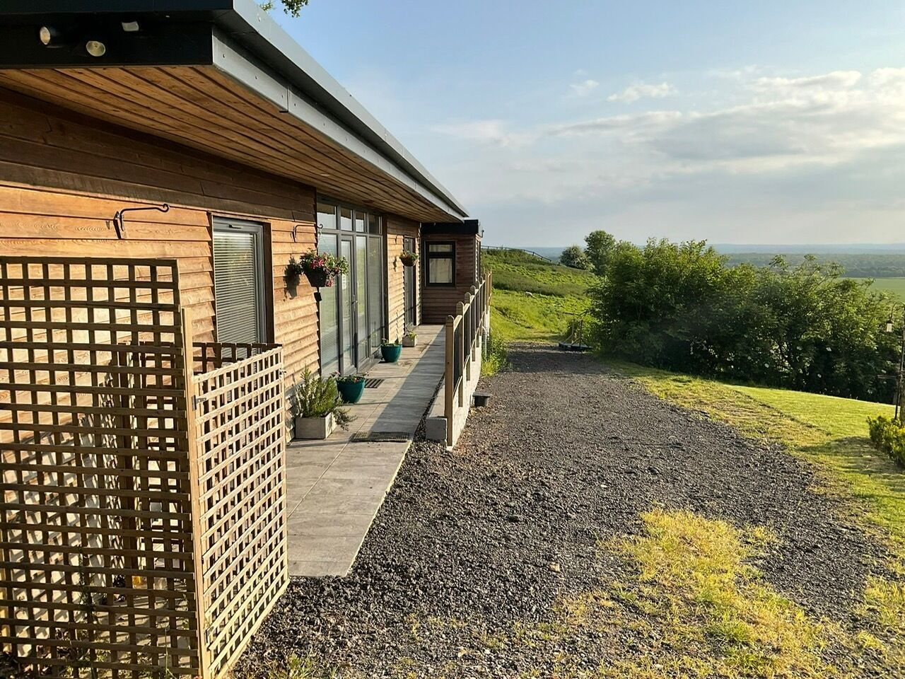 A wooden house with a gravel driveway and a wooden fence.