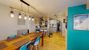 A modern kitchen with a central island, wooden flooring, and pendant lighting. - Zum Storike Nescht (Barr)