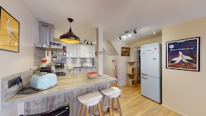 A modern kitchen with a central island, bar stools, a refrigerator, and a dining area. - Zum Storike Nescht (Barr)
