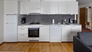 Een moderne keuken met witte kasten, een inbouwoven, een vaatwasser en een koffiezetapparaat.
