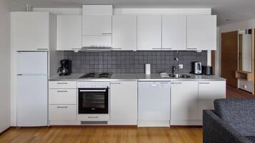 A modern kitchen with white cabinets, a built-in oven, a dishwasher, and a coffee maker.